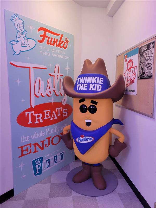 Inside Funmart: A Twinkie the Kid statue stands next to a sign advertising tasty treats for the entire family.